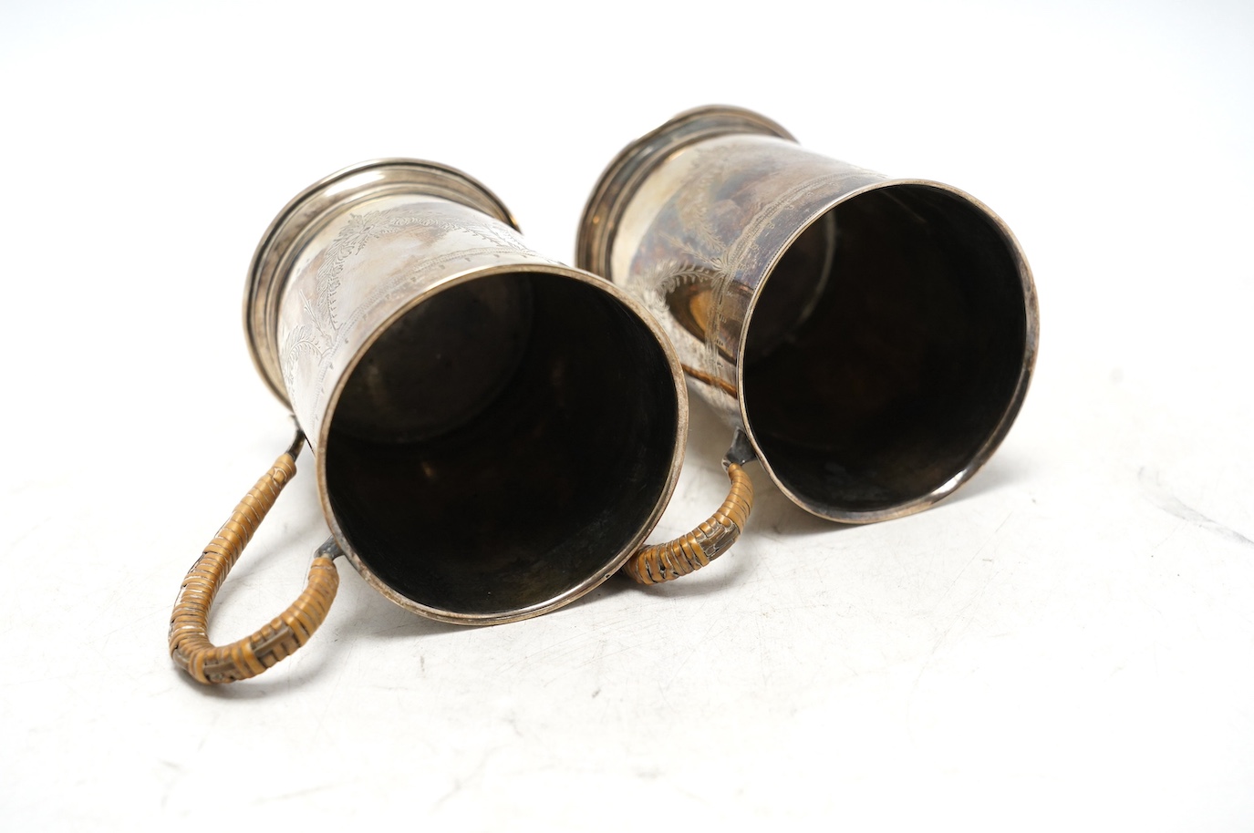 A pair of George V engraved silver mugs, with rattan handles, William Aitken, Birmingham, 1920, height 95mm, gross weight 5.9oz. Condition - fair